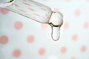 en droppande pipett med en släppa av kosmetika gel. foto