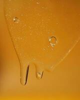 en släppa av kropp gel eller schampo strömmande ner på en gul mättad bakgrund. textur. foto