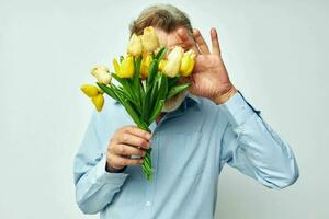 porträtt av Lycklig senior man en bukett av blommor med glasögon som en gåva ljus bakgrund foto