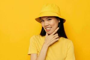 porträtt asiatisk skön ung kvinna tillfällig ha på sig studio hand gest gul bakgrund oförändrad foto