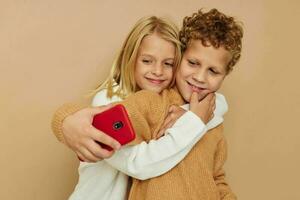 liten pojke och flicka med en röd telefon tillsammans teknik isolerat bakgrund foto