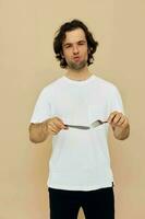 stilig man i en vit t-shirt med kniv med gaffel beige bakgrund foto