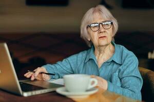 porträtt av ett äldre kvinna i en Kafé en kopp av dryck bärbar dator social nät oförändrad foto
