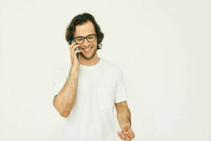 attraktiv man i en vit t-shirt kommunikation förbi telefon isolerat bakgrund foto