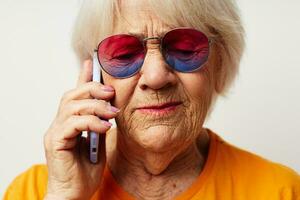 Foto av pensionerad gammal lady i tillfällig t-shirt solglasögon talande på de telefon beskurna se