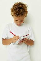 en pojke i en vit t-shirt drar med en penna i en anteckningsbok foto