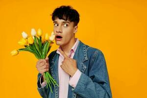 stilig man med bukett av blommor i denim jacka mode gul bakgrund foto