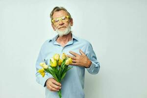 senior gråhårig man i en blå skjorta med en bukett av blommor ljus bakgrund foto