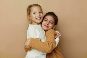 två rolig liten flickor kram vänskap Framställ beige bakgrund foto