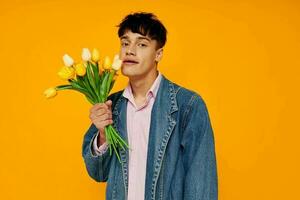 ung kille i denim jacka med en bukett av blommor Framställ roman foto