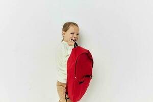 liten flicka röd ryggsäck eleganta kläder isolerat bakgrund foto