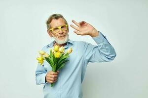 äldre man en bukett av blommor med glasögon som en gåva ljus bakgrund foto