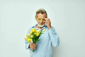 senior gråhårig man i en blå skjorta med en bukett av blommor ljus bakgrund foto