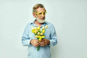 senior gråhårig man i en blå skjorta med en bukett av blommor ljus bakgrund foto