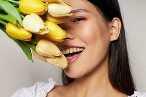 charmig ung asiatisk kvinna med en bukett av blommor leende närbild ljus bakgrund oförändrad foto