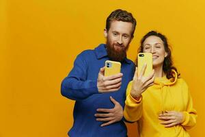 man och kvinna par leende glatt med telefon i hand social media visning foton och videoklipp, på gul bakgrund, symboler tecken och hand gester, familj frilansare.