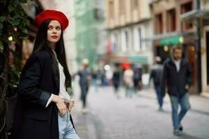 kvinna mode modell promenader på de gata i de stad Centrum bland de folkmassan i en jacka och röd basker och jeans, filmiska franska mode stil Kläder, resa till istanbul foto