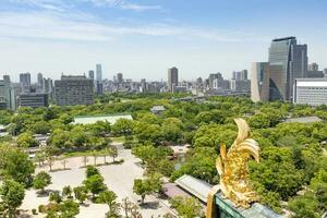 hög vinkel se från de topp av osaka slott med hustak och guldfisk kommer ner runt om de stad. foto