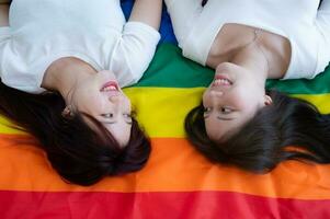 på en regnbåge flagga, ett HBTQ par lyckligt lögn ner, chattar, och kitslig varje Övrig. foto