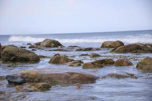 vågor som tvättar över klipporna vid havet på sommaren