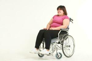 fett asiatisk kvinna lider från övning skador hon var Sammanträde i en rullstol. vikt förlust övning begrepp. hälsa försäkring. vit bakgrund foto