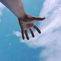 handen uppåt och når den blå himlen foto