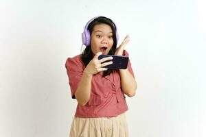 spelar mobil spel på smartphone med hörlurar av skön asiatisk kvinna isolerat på vit foto