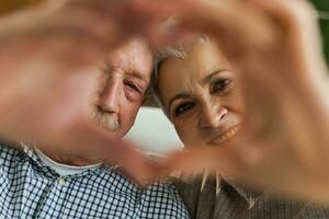 kärlek hjärta form fred. senior äldre par framställning hjärta form med deras händer. vuxen mogna gammal Make fru som visar hjärta tecken. Lycklig pensionär familj. jag kärlek du Lycklig valentines dag. foto