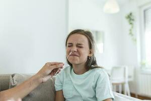 mor är tar snabb covid-19 testa på Hem till henne sjuk dotter på Hem. mamma testning ung flicka för coronavirus infektion tar snabb covid-19 testa foto