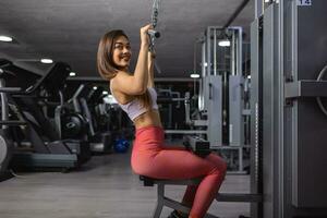 kondition kvinna arbetssätt ut i Gym håller på med övning för tillbaka. atletisk flicka håller på med lat dra ner foto