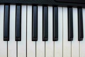 närbild av piano nycklar. piano svart och vit nycklar och piano tangentbord musikalisk instrument placerad på de Hem balkong under solig dag. foto