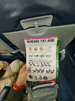 Bangkok, thailand på Maj 21, 2023. en hand är innehav en säkerhet instruktion ark för en boeing 737-800 flygplan foto
