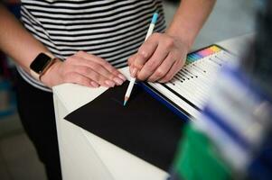 närbild se av kvinnas hand testning Färg penna, teckning på en svart papper ark. skola pappersvaror. teckning leveranser foto