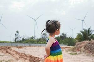 asiatisk flickor studie vind turbiner till generera elektricitet. hållbar energi. framtida. foto