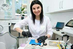 erfaren leende kvinna protes- ingenjör, dental tekniker Arbetar med plåster forma kasta av mänsklig käke. ortodonti foto