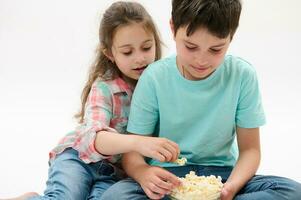 närbild härlig barn barn - preteen pojke och söt bebis flicka äter popcorn, isolerat över vit studio bakgrund foto