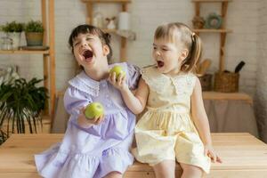 liten Lycklig flickor lura runt om i de kök och äta äpplen foto
