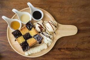 honungskål med vaniljglass, vispad grädde och chokladsirap. serveras med banan foto
