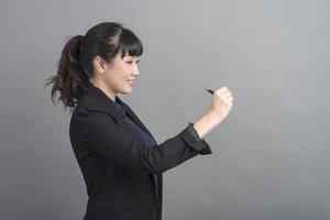vacker affärskvinna som skriver något på grå bakgrund foto