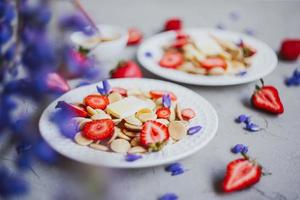 pannkakaflingor, trendig mat. mini spannmålspannkakor med smör, honung och jordgubbar. foto