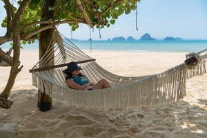 ung asiatisk kvinna som sover på hängmattan nära stranden under sommarsemester