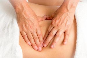 massageterapeut som masserar kvinnans mage foto