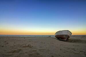 ensam gammal båt på de strand på solnedgång. horisontell se foto