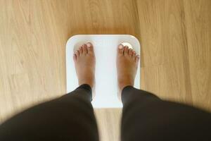 tappa bort vikt. fett diet och skala fötter stående på elektronisk skalor för vikt kontrollera. mått instrument i kilogram för diet. foto