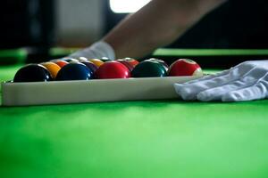 mannens hand och kö ärm spelar snooker spel eller framställning siktar till skjuta slå samman bollar på en grön biljard tabell. färgrik snooker bollar på grön fris. foto