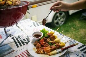 vänner framställning utegrill bbq grillning över en varm brand i de natur.middag fest foto