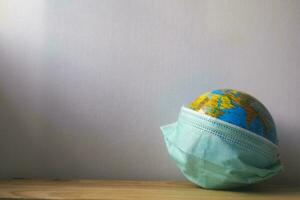 värld globus med grön medicinsk mask på den foto