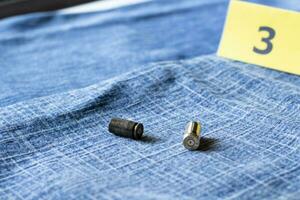 9mm pistol kula skal på suddig blå jeans och siffra ett bakgrund, begrepp för undersökning av offer och brottslighet händelse av poliser. mjuk fokus. foto