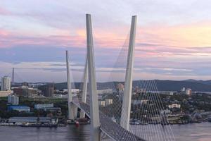 stadslandskap med utsikt över den gyllene bron vid solnedgången Vladivostok Ryssland foto