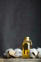 bomullsfrö olja i en glas flaska på en trä- yta. foto